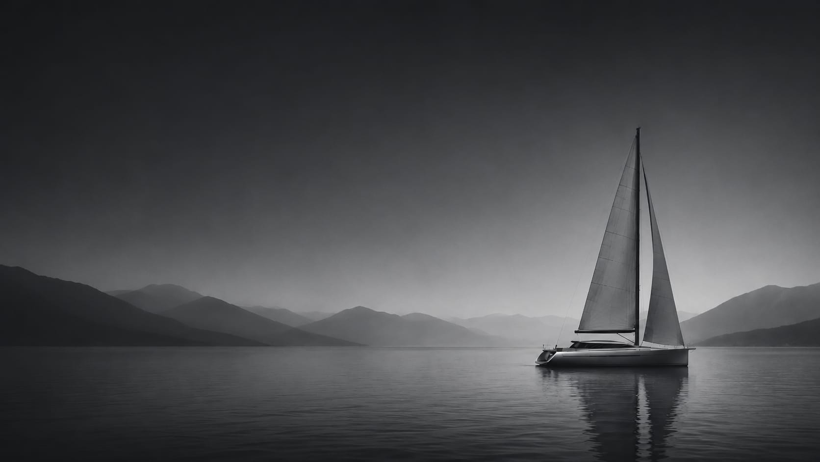 A sailboat on calm open water with hazy mountains on the horizon, in grayscale